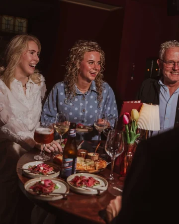 Drie gasten aan tafel met gerechten en een lampje